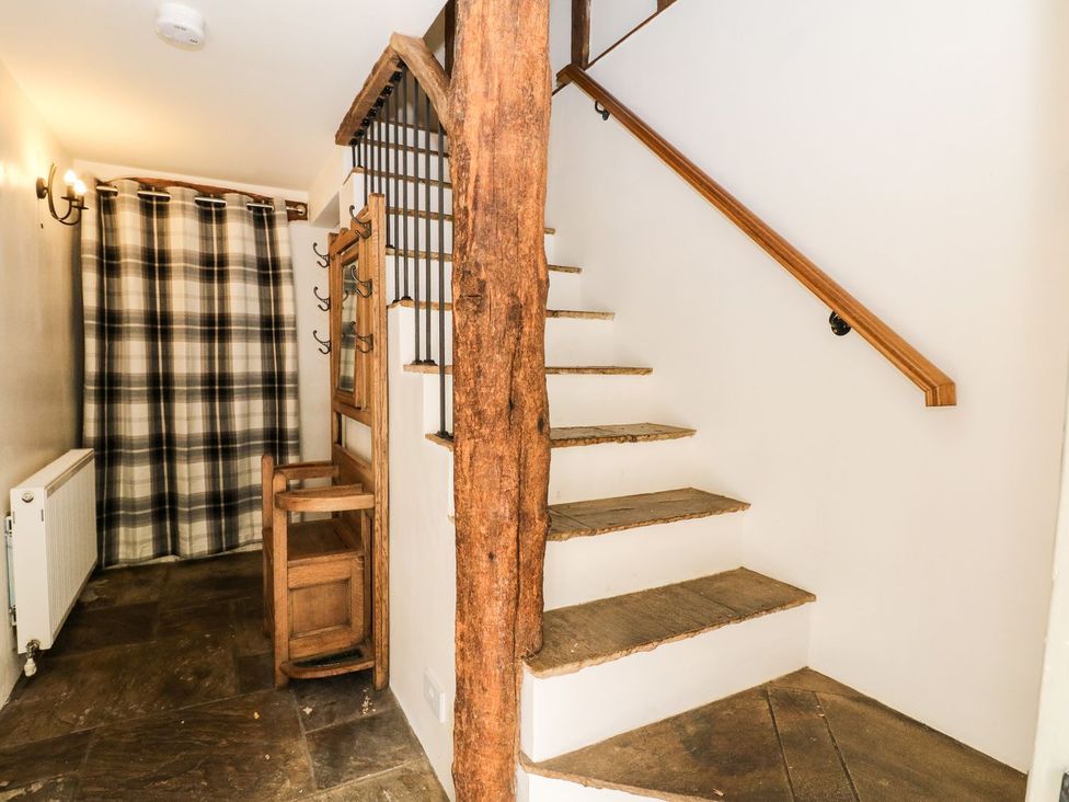 A hallway with a staircase and a coat rack at The Barn