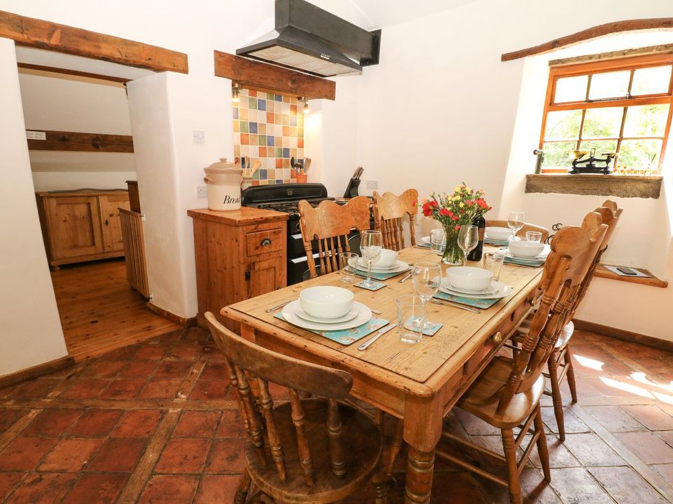 A dining table with chairs and kitchen appliances at The Barn