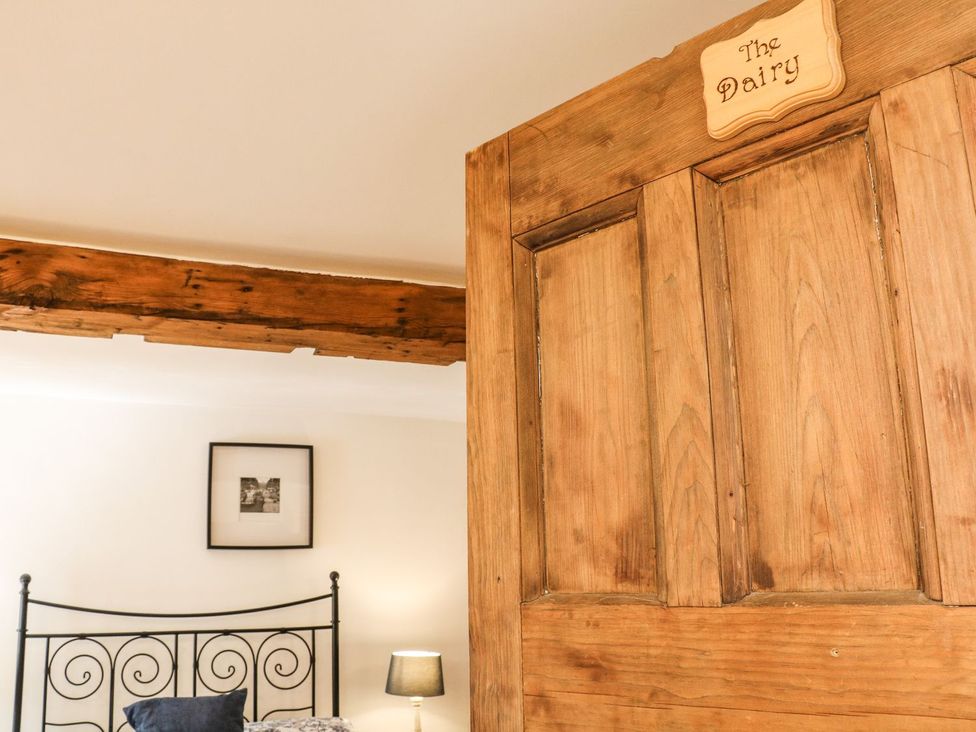 A door leading to a bedroom with a bed and a lamp at The Barn 