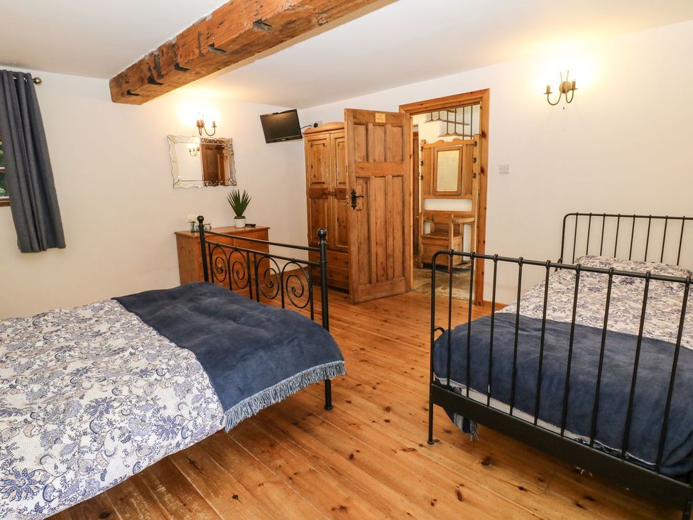A bedroom with two beds and a wooden cabinet at The Barn 