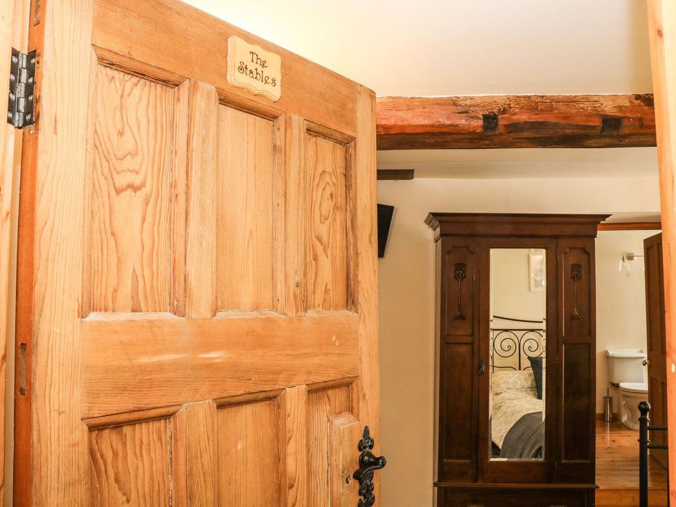 A wooden door opening to a bedroom with a bed and a mirror at The Barn