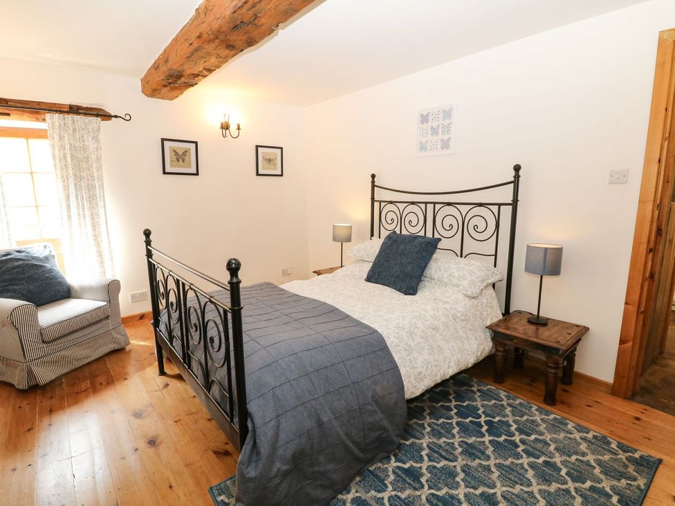 A bedroom with a bed and armchair at The Barn in 