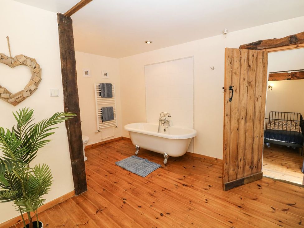 A bathroom with a bathtub and wooden door at The Barn 