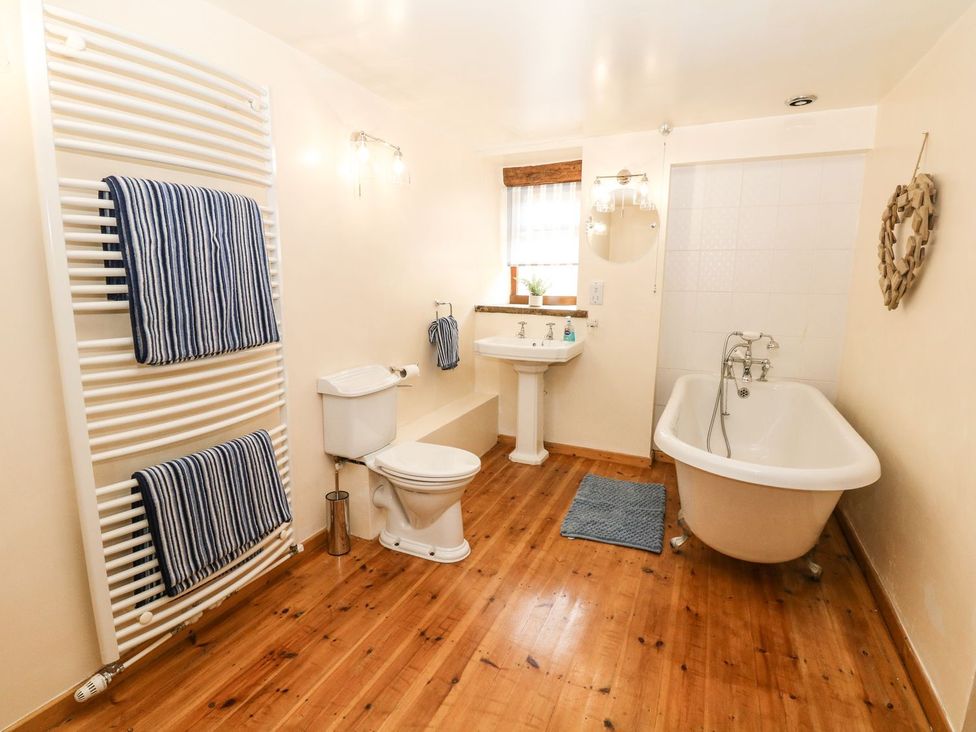 A bathroom with a bathtub, toilet, and wash basin at The Barn in 