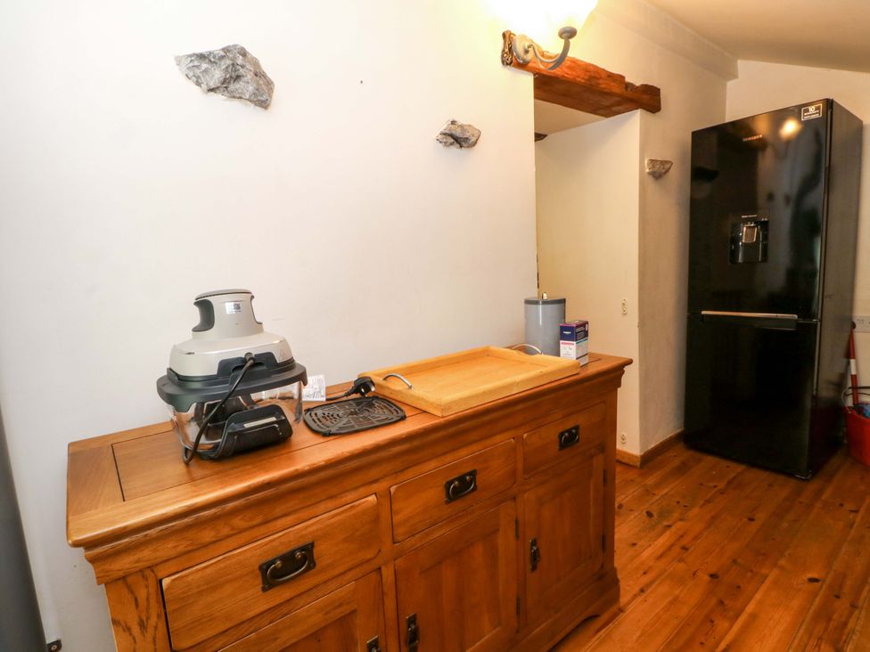 A kitchen with a wooden cabinet and a refrigerator at The Barn in Miller's Dale near Tideswell