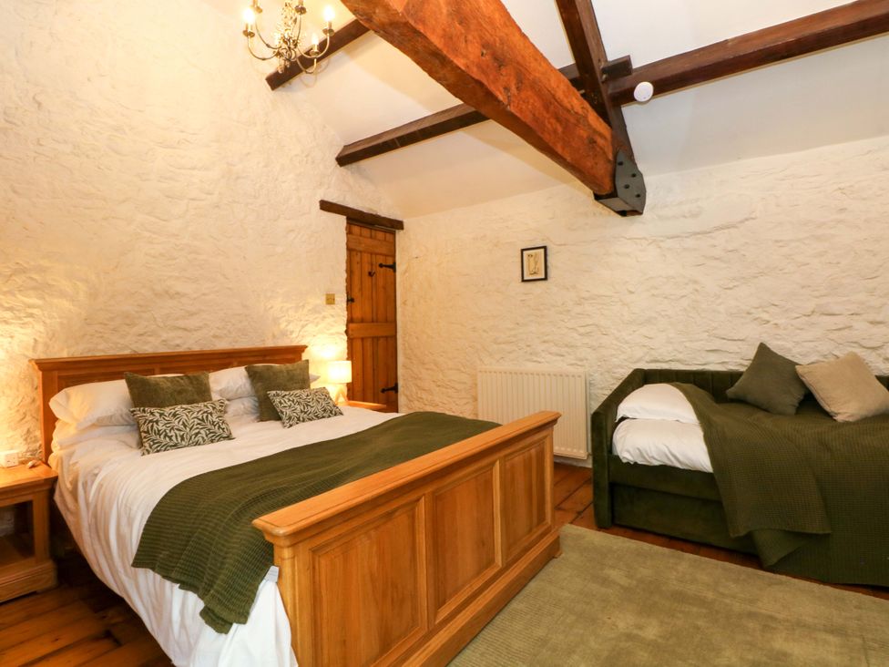 A bedroom with a bed and sofa at The Barn in Miller's Dale near Tideswell