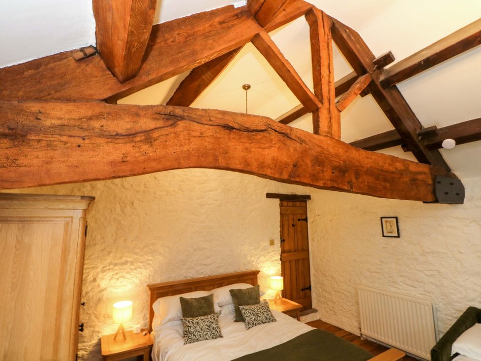 A bedroom with wooden beams and a bed at The Barn in Miller's Dale near Tideswell