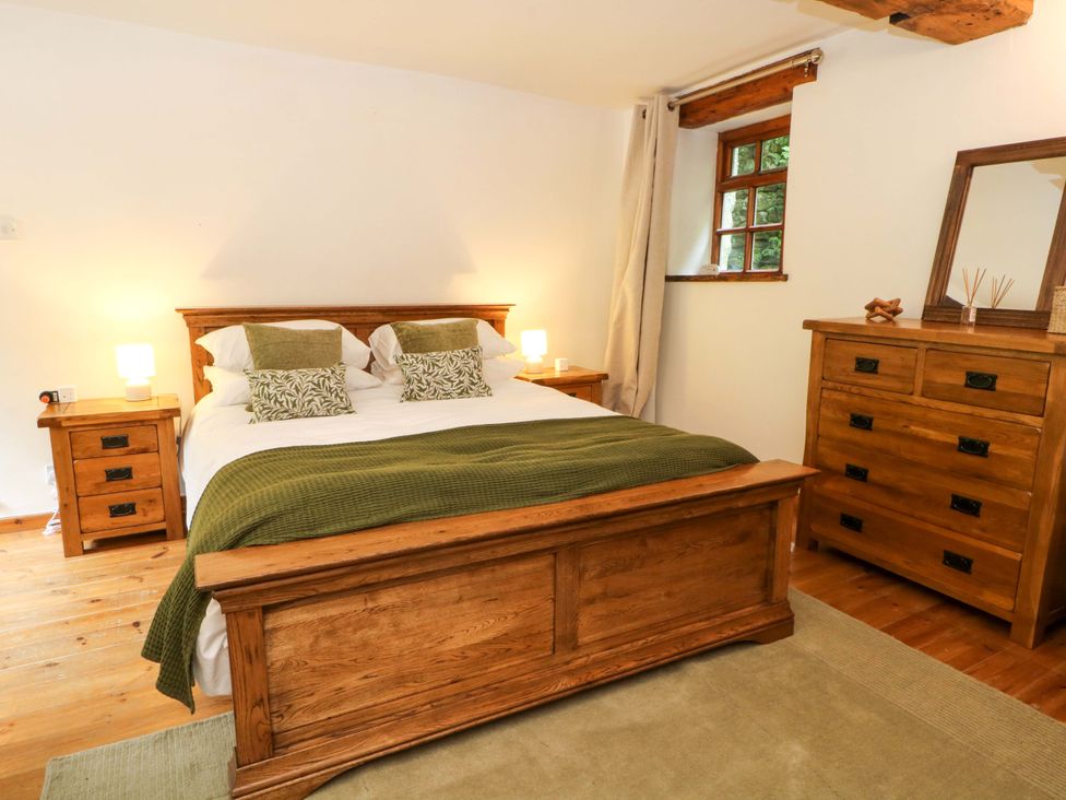 A bedroom with a bed and wooden furniture at The Barn in Miller's Dale near Tideswell