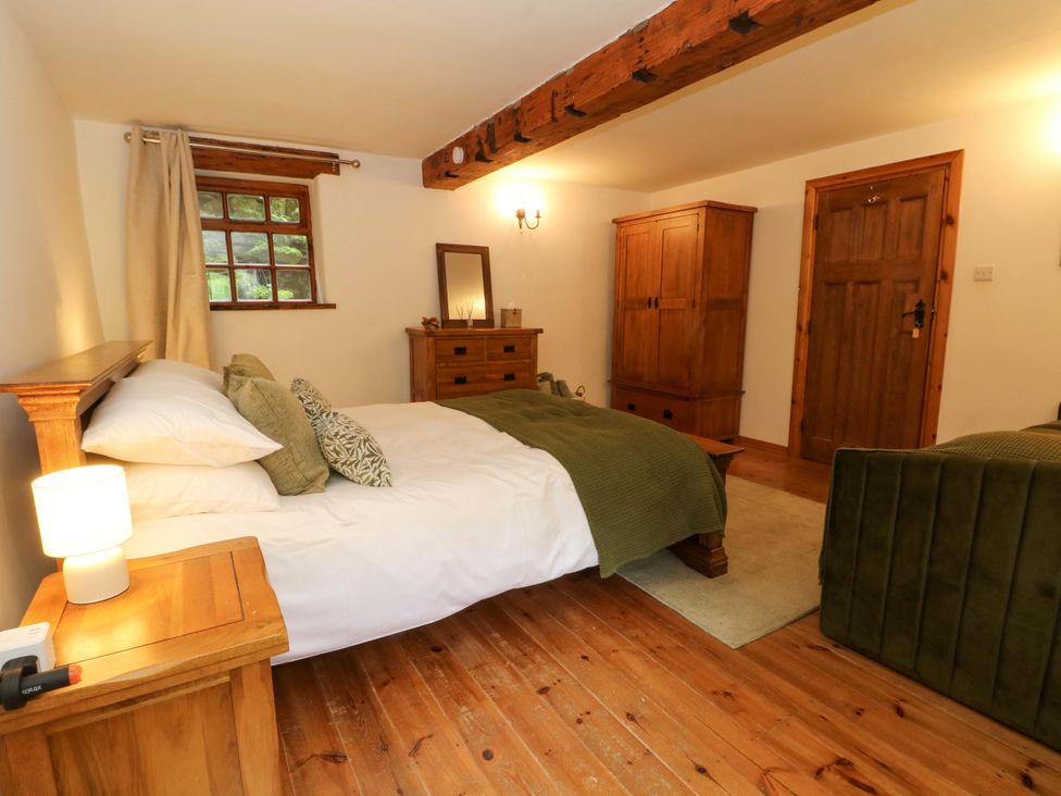 A bedroom with a bed and wooden furniture at The Barn in Miller's Dale near Tideswell