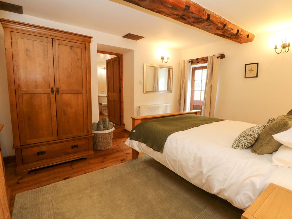 A bedroom with a bed and wardrobe at The Barn in Miller's Dale near Tideswell