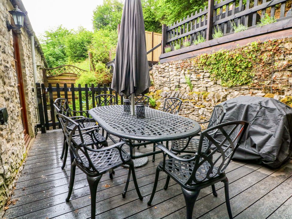 An outdoor area with a table and chairs under an umbrella at The Barn in Miller's Dale near Tideswell