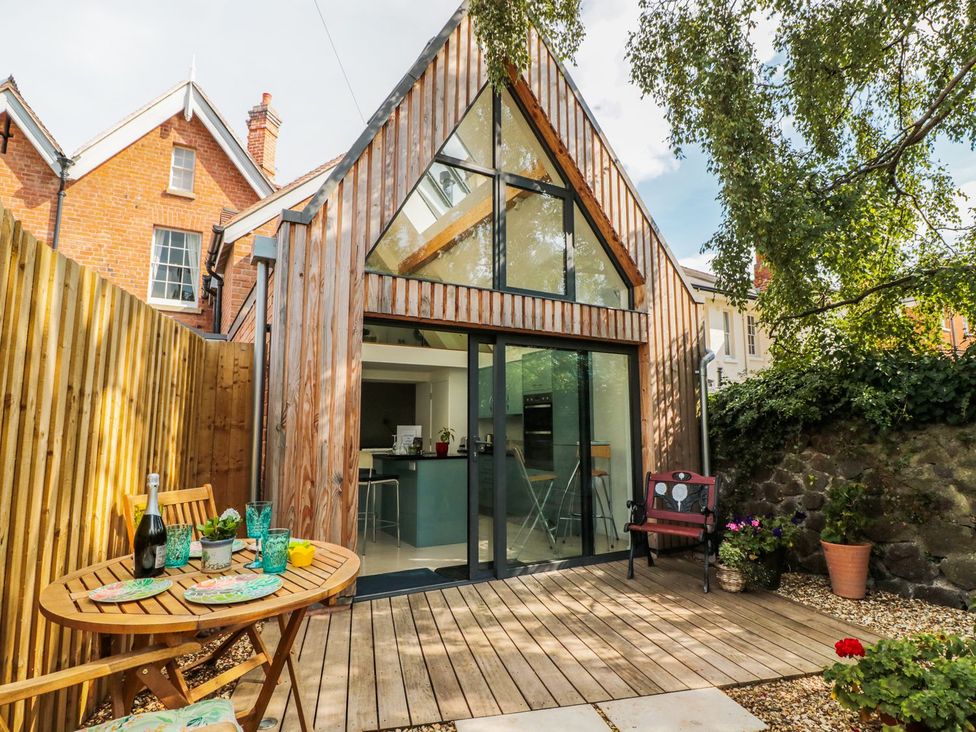 A garden with a wooden deck and seating area at Little Mornington in Malvern