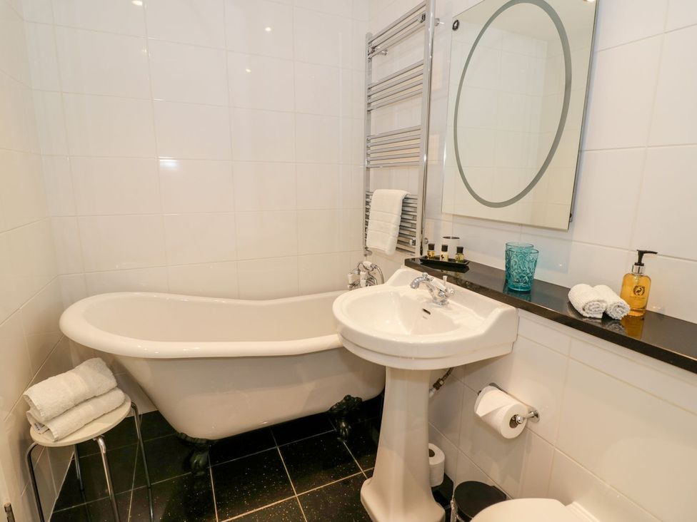 A bathroom with a bathtub, sink, and towel rack at Little Mornington, Malvern