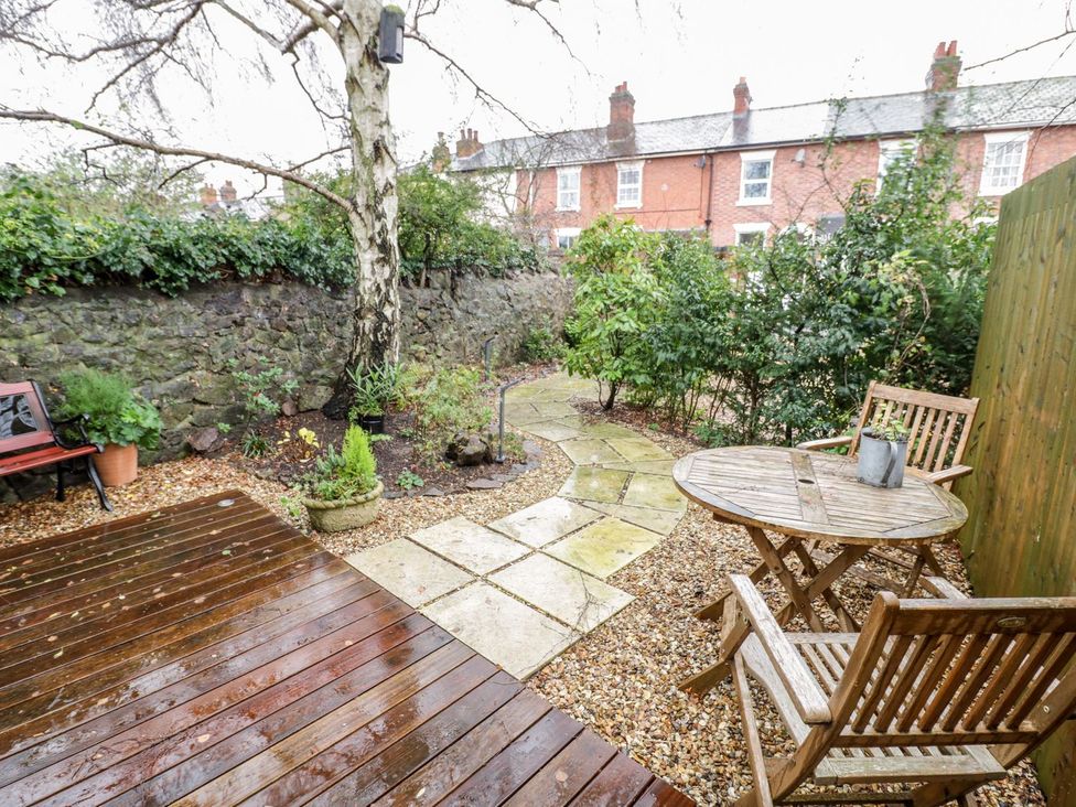 A garden with a wooden table and chairs at Little Mornington in Malvern