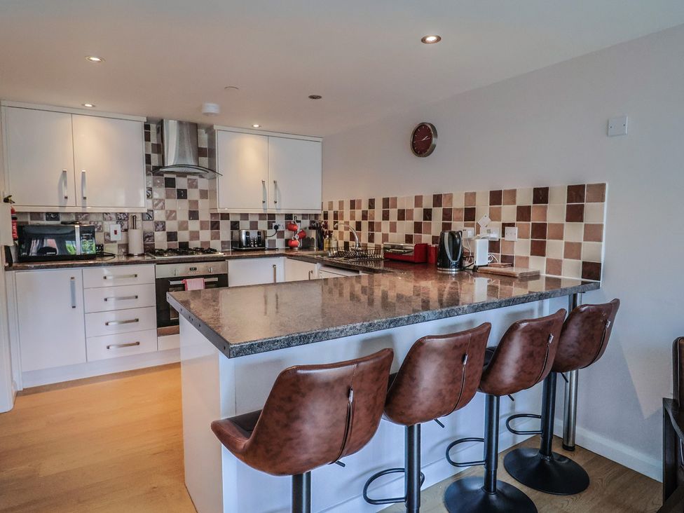 A kitchen with a counter and stools at Beck House in Weymouth