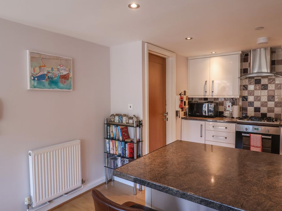 A kitchen with appliances and a shelving unit at Beck House in Weymouth