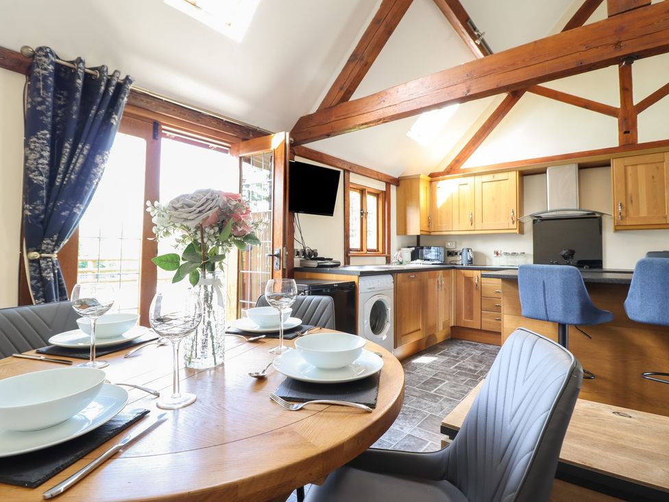 A kitchen with dining area and washing machine at Ysgubor Fachwen in Newtown