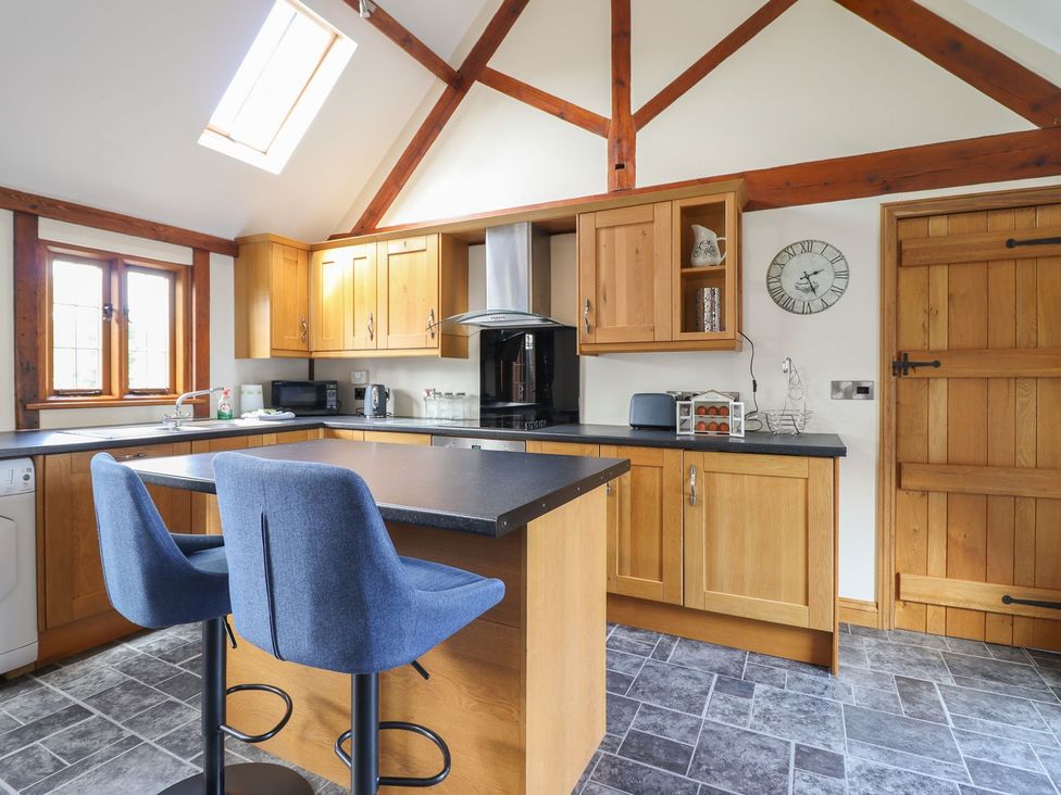 A kitchen with wooden cabinets and a counter at Ysgubor Fachwen in Newtown