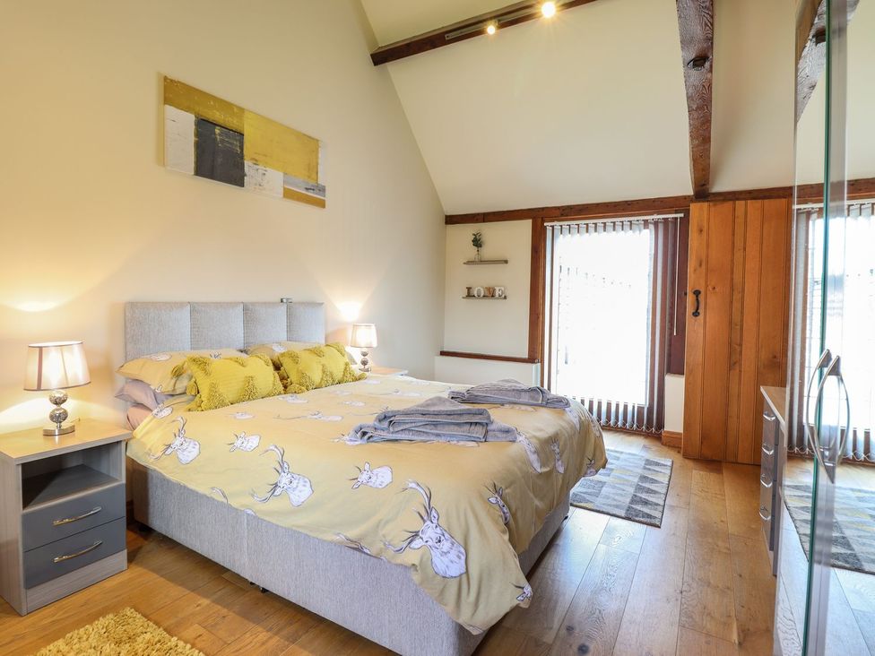 A bedroom with a bed and nightstand at Ysgubor Fachwen in Newtown