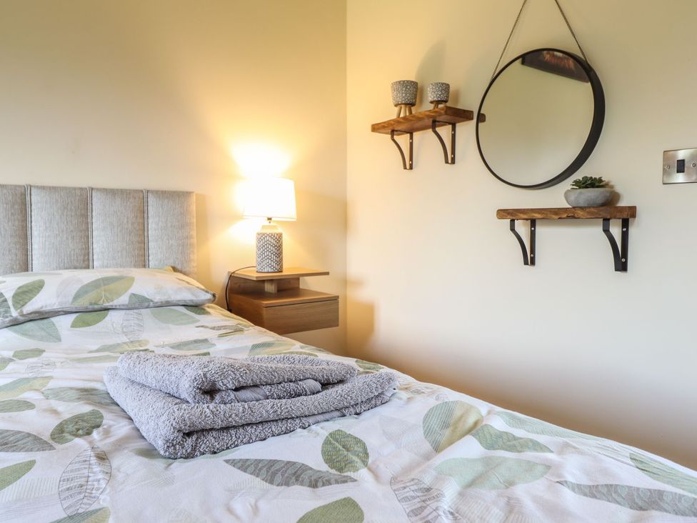 A bedroom with a bed, lamp, and mirror at Ysgubor Fachwen in Newtown