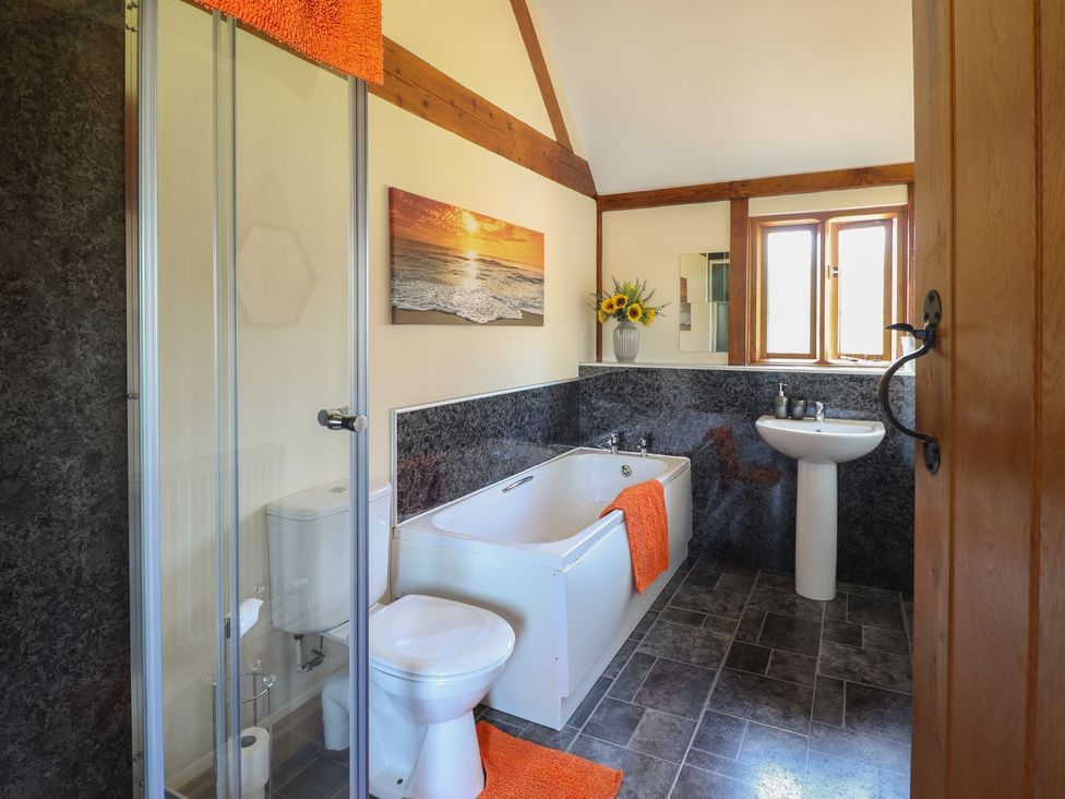 A bathroom with a bathtub, sink, and shower at Ysgubor Fachwen, Newtown