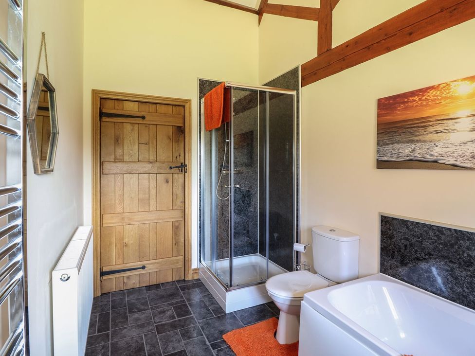 A bathroom with a shower and bathtub at Ysgubor Fachwen in Newtown