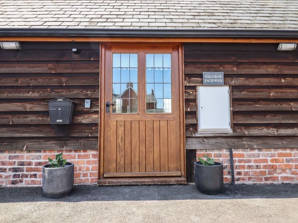 A front door with a mailbox and plant pots at Ysgubor Fachwen Newtown
