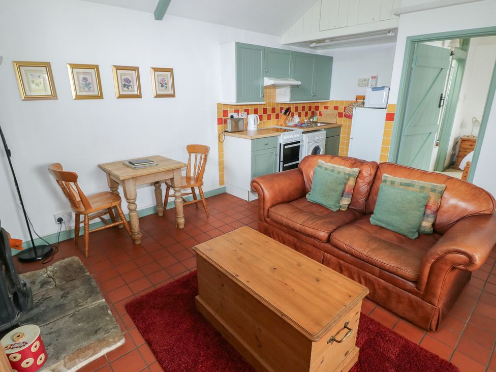 A living room with a sofa and dining area at Warbler Cottage in Cowbridge