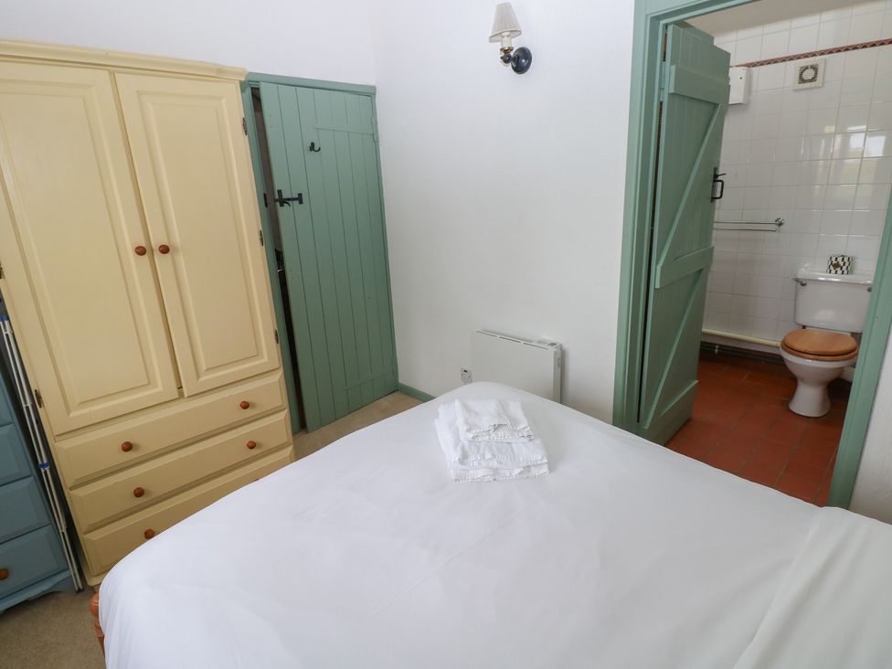 A bedroom with a bed and wardrobe at Warbler Cottage in Cowbridge