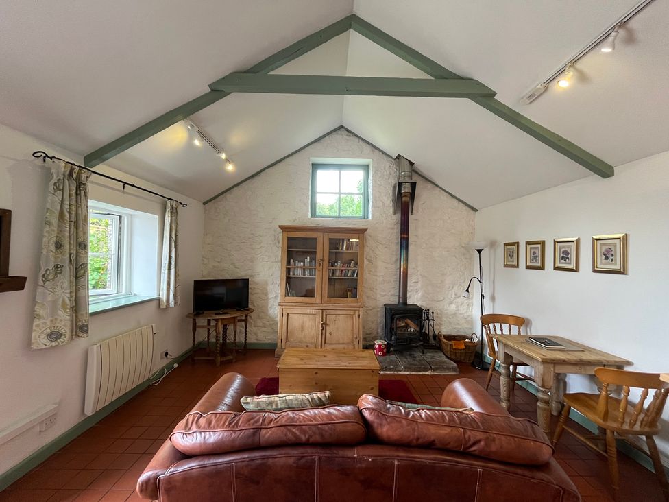 A living room with a sofa, table, and fireplace at Warbler Cottage near Cowbridge