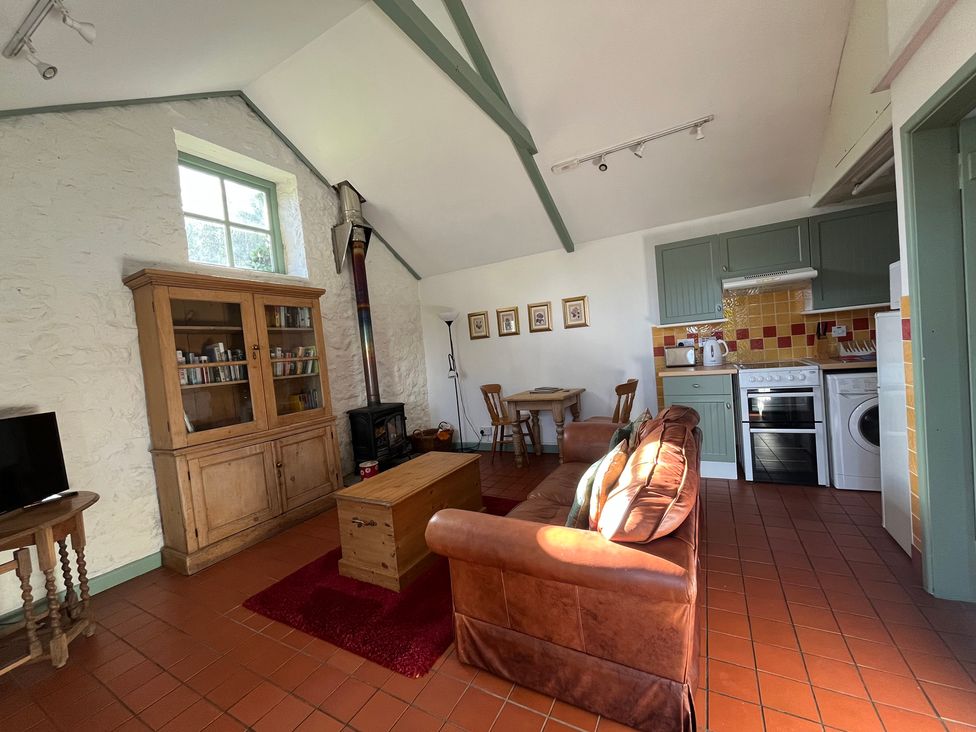 A living room with a sofa and kitchen area at Warbler Cottage near Cowbridge