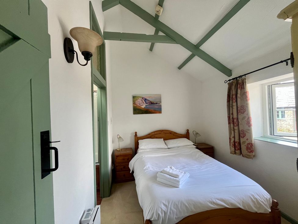 A bedroom with a bed and window at Warbler Cottage near Cowbridge
