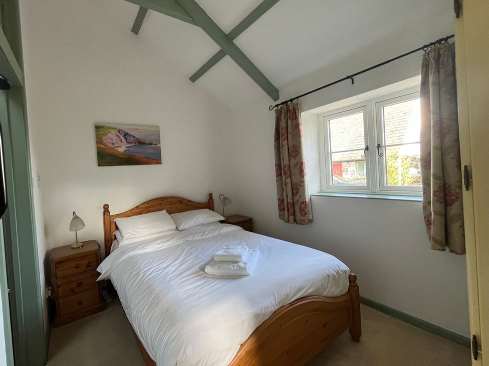 A bedroom with a bed and a nightstand at Warbler Cottage near Cowbridge