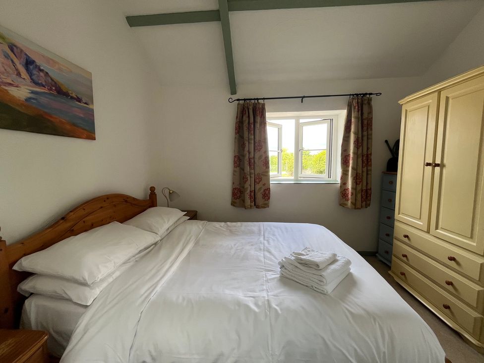 A bedroom with a bed and wardrobe at Warbler Cottage near Cowbridge