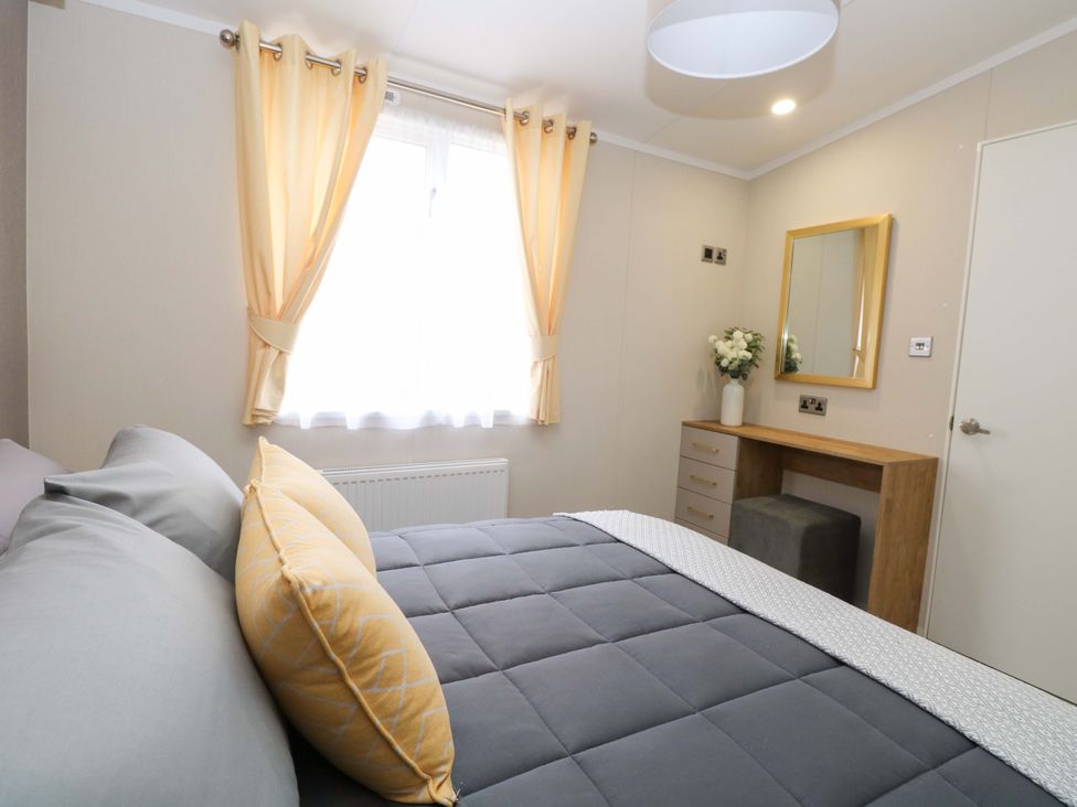 A bedroom with a bed and dressing table at The Honey Pot Retreat in Fritton near Belton, Norfolk