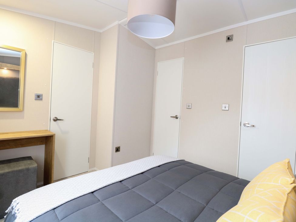 A bedroom with a bed and a mirror at The Honey Pot Retreat in Fritton near Belton, Norfolk