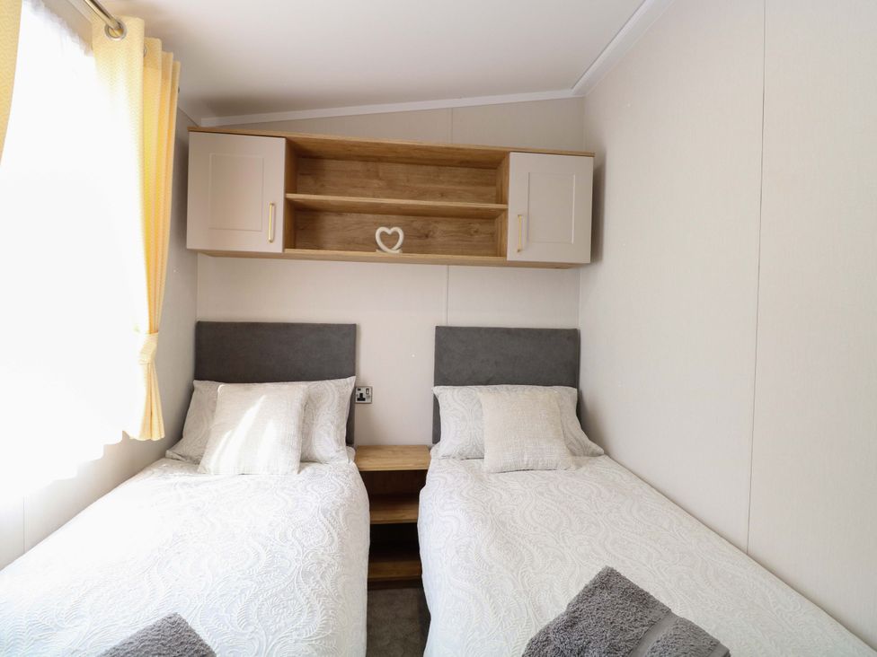 A bedroom with two beds and a shelf at The Honey Pot Retreat in Fritton near Belton, Norfolk