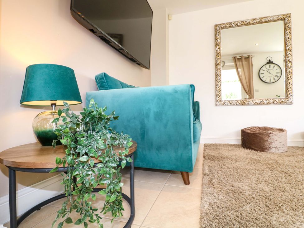 A living room with a teal sofa, lamp, and mirror at 16 Temple Crescent Nuthall