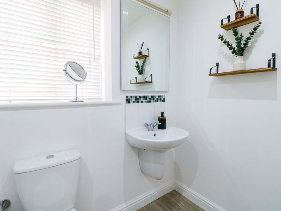 A bathroom with a toilet, a sink, and shelves at 16 Temple Crescent Nuthall