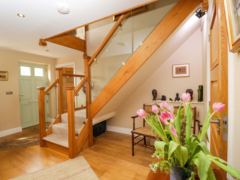 A hallway with a staircase and a vase of flowers at Ormiston House in Netheravon