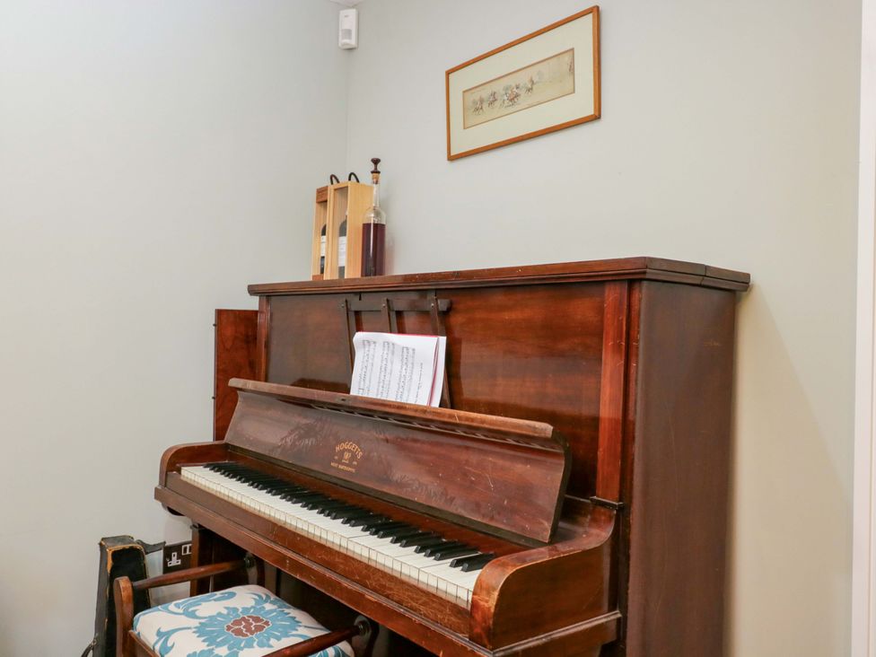 A piano with sheet music and a picture on the wall at Ormiston House in Netheravon