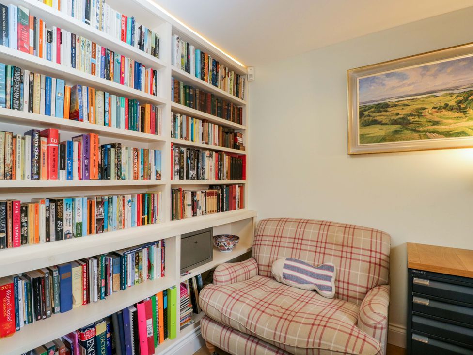 A study with bookshelves and a chair at Ormiston House in Netheravon