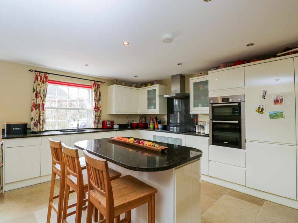 A kitchen with bar stools and appliances at Ormiston House in Netheravon