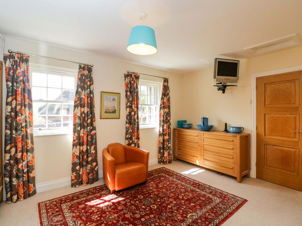 A living room with an armchair and a TV at Ormiston House Netheravon