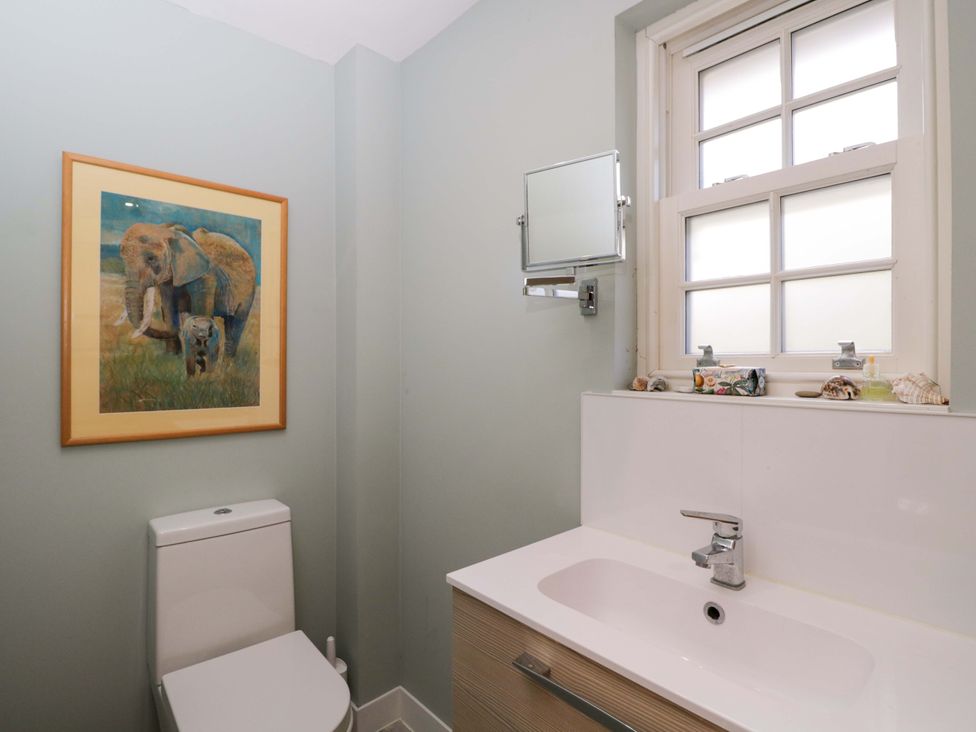 A bathroom with a toilet, mirror, and sink at Ormiston House in Netheravon