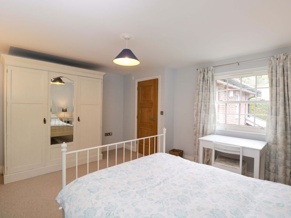 A bedroom with a bed, wardrobe, desk, and window at Ormiston House in Netheravon
