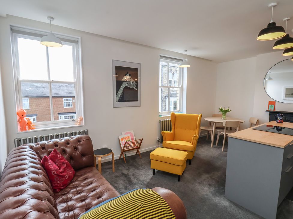 A living room with a sofa, chair, and dining table at Nancy’s Blushes Saltburn-by-the-Sea