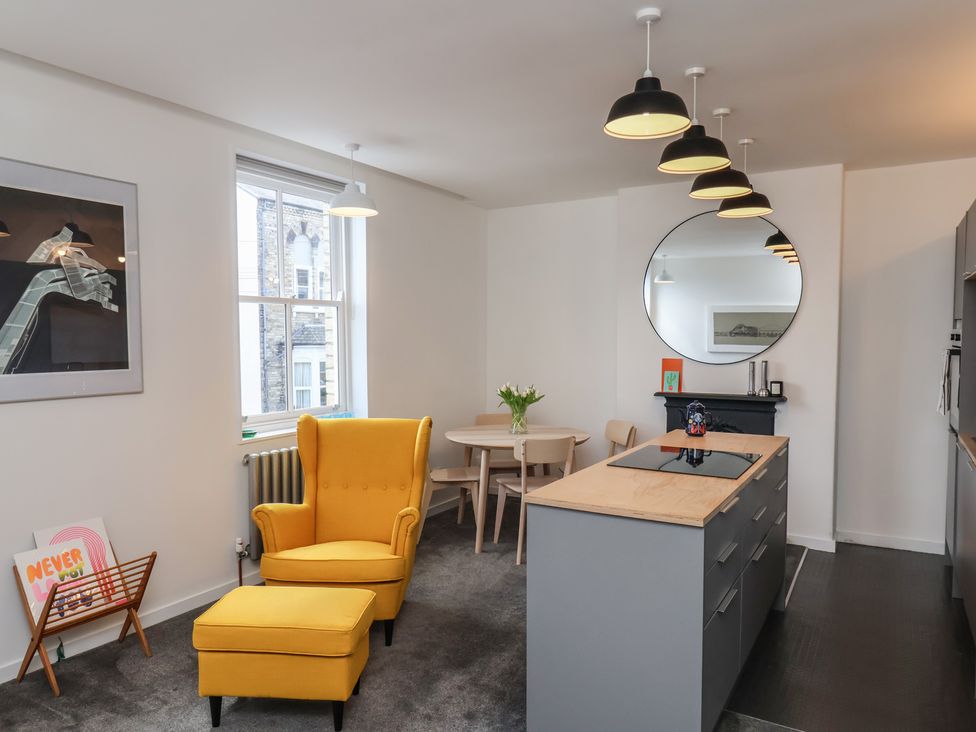 A kitchen with a yellow armchair and dining table at Nancy’s Blushes in Saltburn-by-the-Sea