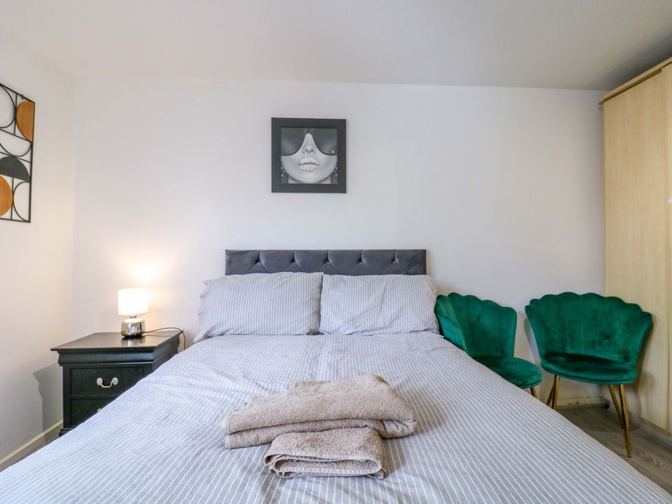 A bedroom with a bed, bedside table, lamp, and chairs at 22A Warrender Road in Tufnell Park