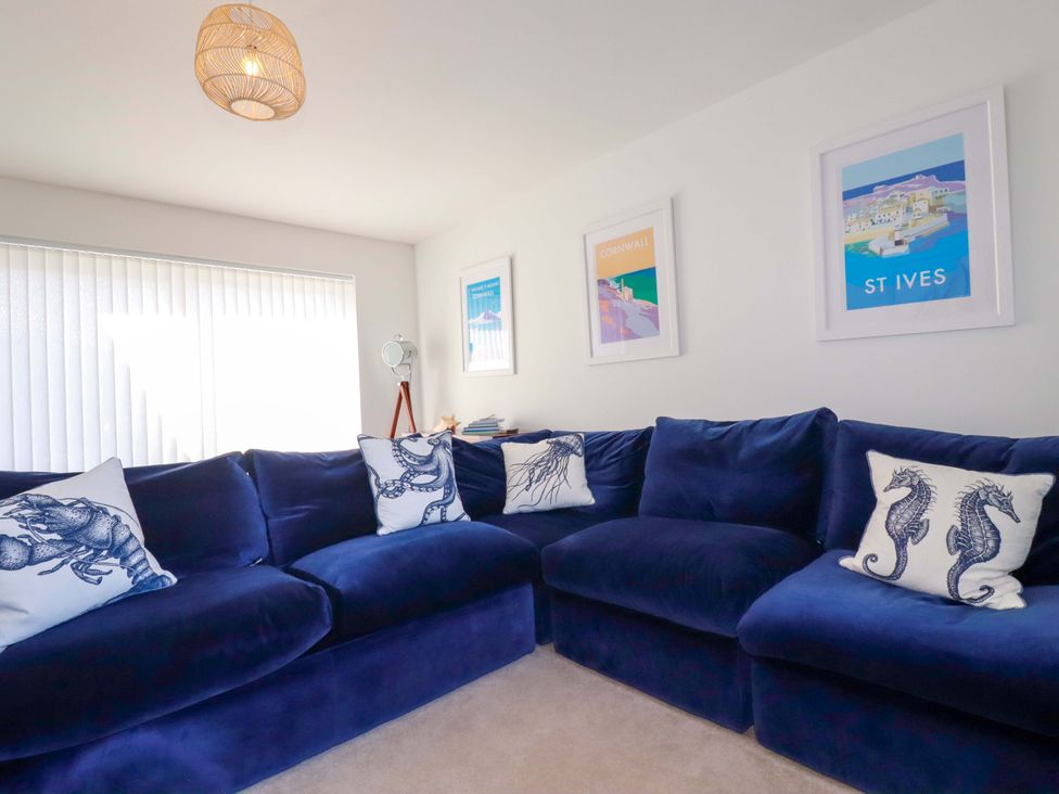 A living room with a blue sofa and artwork on the walls at Serfaus in Perranporth